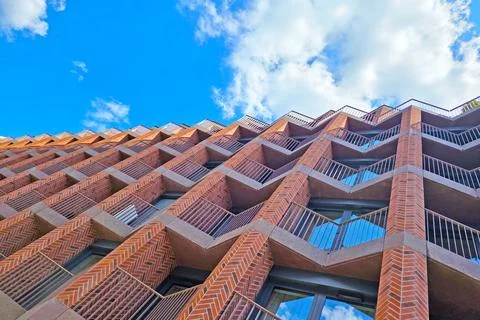 Modern Architectural Design of Brick Facade Skyscraper Against Blue Sky Stock Photos
