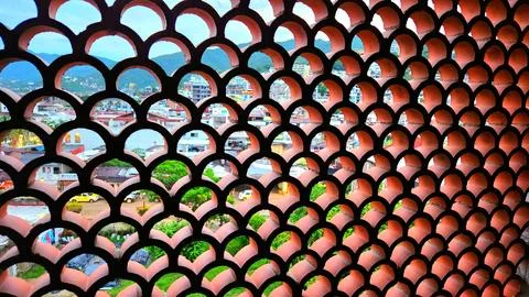 Modern architectural design features a patterned wall overlooking a city la.. Stock Photos