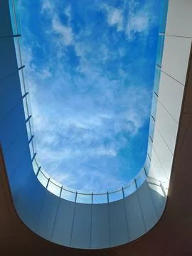 A modern architectural structure with a deep oval skylight capturing the sky Foto stock