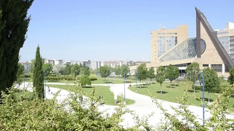 Modern architecture building from a hill with bushes, with people walking Stock Footage