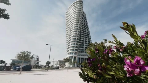 Modern architecture showcases sleek tower surrounded by vibrant flowers Stock Footage 302352241