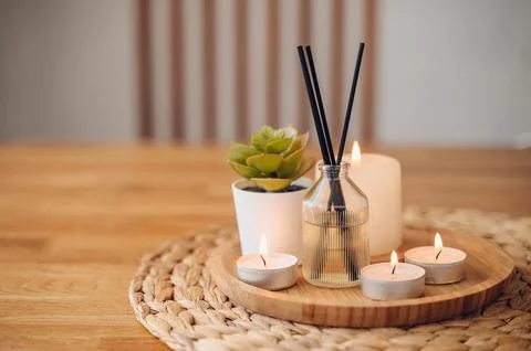 Modern aroma diffuser with bamboo reeds and burning candles on a round tray.. Stock Photos