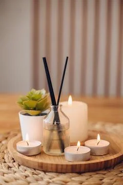 Modern aroma diffuser with bamboo reeds and burning candles on a round tray.. Stock Photos