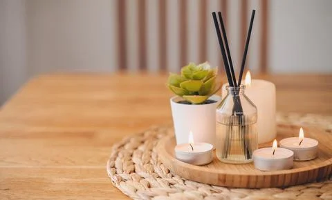 Modern aroma diffuser with bamboo reeds and burning candles on a round tray.. Stock Photos
