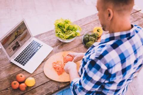 Modern attractive man watching a tutorial video in the kitchen Stock Photos