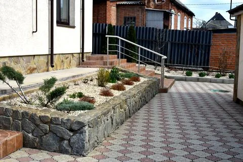 Modern backyard landscape design with stone raised garden bed, decorative plants Stock Photos