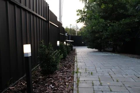 Modern backyard pathway illuminated by small electric lights at dusk in summe Stock Photos