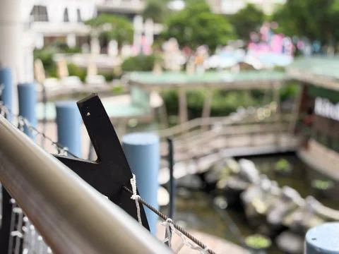A modern balcony railing featuring a dark geometric metal bracket and wire mesh Stock Photos