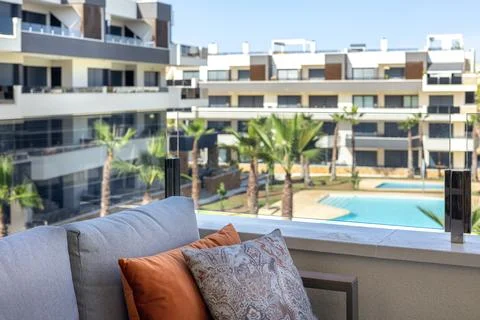 Modern balcony sofa with patterned pillows overlooking apartment pool area Stock Photos