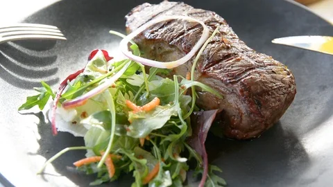 Modern barbecue dry aged sliced fillet steak with salad on a black plate  動画素材 102002386