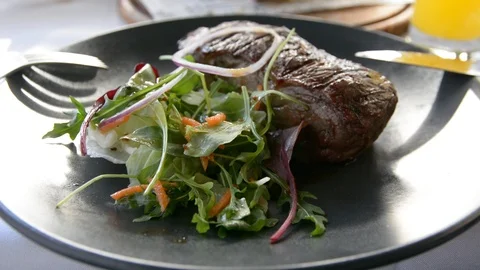 Modern barbecue dry aged sliced fillet steak with salad on a black plate  Видео 102002802