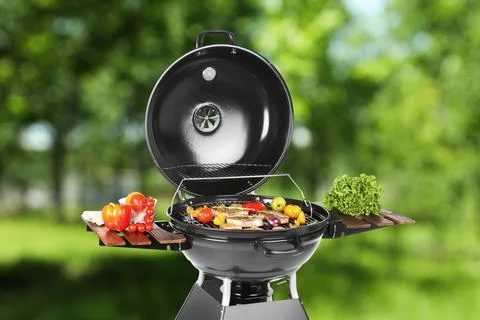 Modern barbecue grill with tasty food outdoors on sunny day Stock Photos