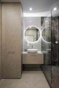 Modern bathroom with backlit round mirror Stock Photos