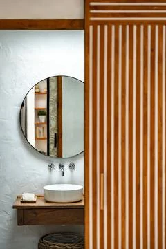 Modern bathroom design featuring a circular mirror and wooden accents Stock Photos