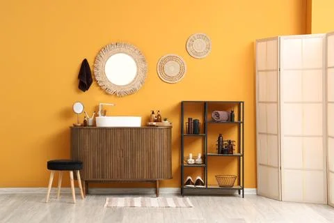Modern bathroom interior design with orange wall, wooden vanity, white sink,  Stock Photos