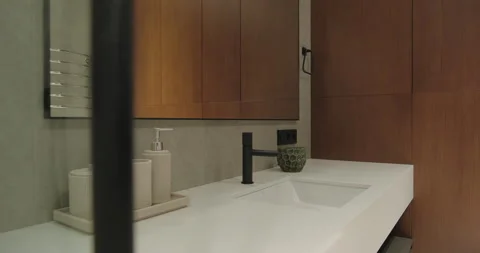 Modern bathroom interior design with sink faucet mirror wooden cabinet light Stock Footage 277226980