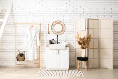 Modern bathroom interior design with white brick wall, wooden clothes rack, v Stock Photos