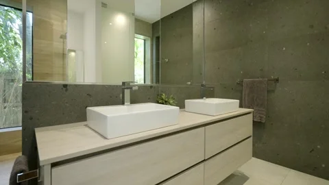 Modern bathroom interior with large mirror on wall reflecting opposite side of Stock Footage 294906878