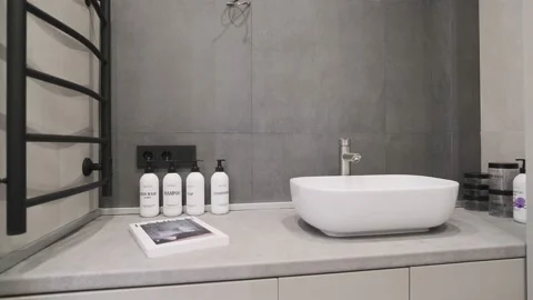 Modern bathroom interior with minimalist lighting. White sink with many jars for Stock Footage 233943491