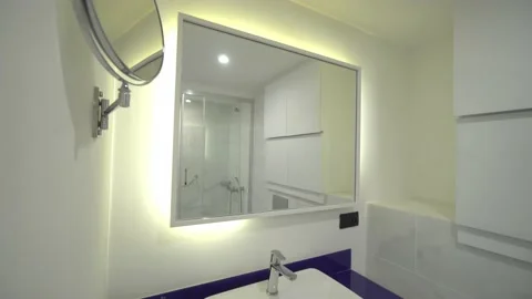 Modern bathroom with light white dressing table, mirror frame and accessories. 库存影片 171596188
