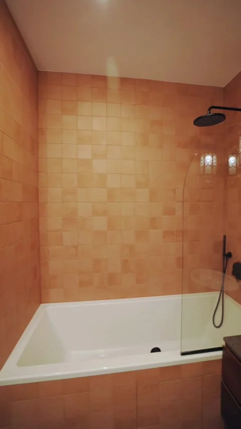 Modern bathroom with orange tiles bathtub and black fixtures Stock Footage 331770053