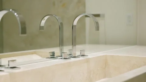 Modern bathroom sink with two sleek, chrome faucets. Light-colored stone Stock Footage 294853733