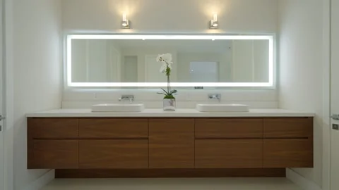 Modern bathroom vanity with large mirror framed by bright led light. Two white Stock Footage 276026734