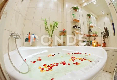 Modern bathroom in warm tones with jacuzzi and rose petals wide angle view Stock Photos