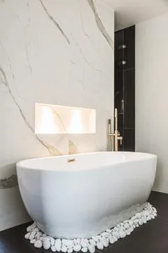Modern bathroom with white bathtub surrounded with white stones Stock Photos