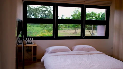 Modern bedroom with large window overlooking a lush garden 스톡 동영상 341684705