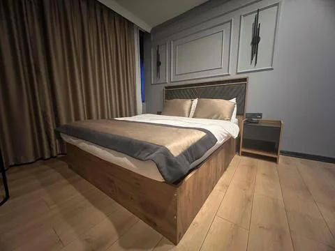 Modern bedroom with made bed, grey walls, wooden floor. concept hotel, interi Stock Photos