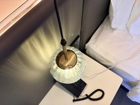 Modern bedside lamp with remote control on a white table. Stock-Fotos