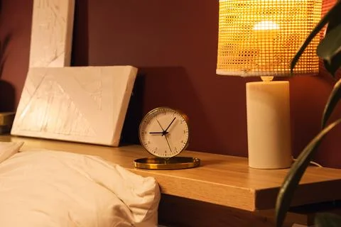 Modern bedside table with clock and lamp Stock Photos
