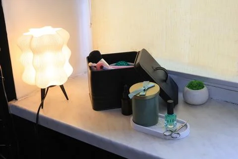 Modern bedside table setup with a unique lamp and beauty essentials Stock Photos