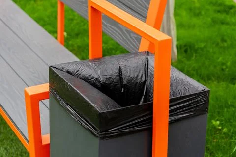 A modern bench featuring a built-in garbage container with a black liner Stock-Fotos
