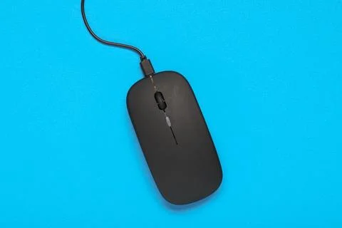 Modern black computer mouse on blue background Stock Photos