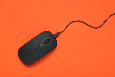 Modern black computer mouse on orange background Stock Photos