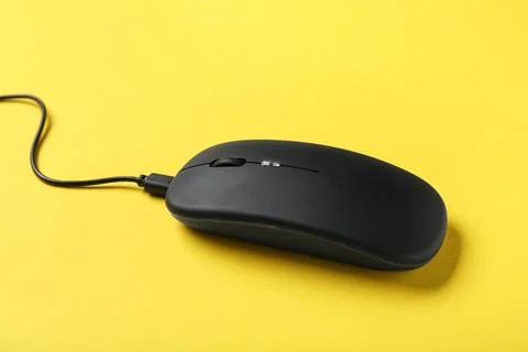 Modern black computer mouse on yellow background Stock Photos
