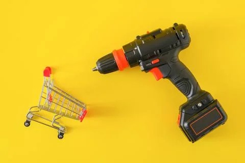 Modern black cordless screwdriver with empty shopping cart Stock Photos