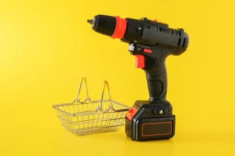 Modern black cordless screwdriver with empty shopping basket Stock Photos