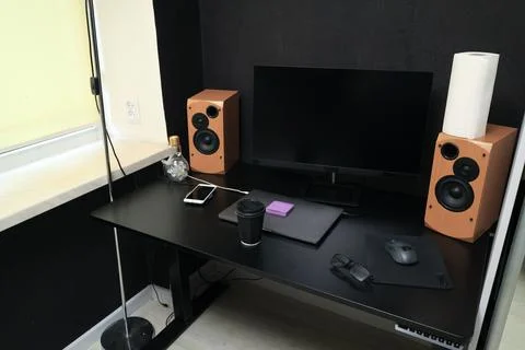 Modern black desk setup with computer monitor, speakers, and laptop Stock Photos
