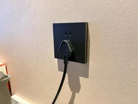 Modern Black Electrical Outlet with Plug on Beige Wall Stock Photos