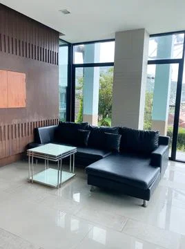 Modern black leather sectional sofa with glass coffee table in a bright Stock Photos