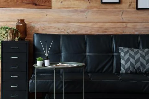 Modern black leather sofa with side table and decorative elements in cozy liv Stock Photos