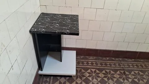 Modern black marble side table sitting in tiled corner space Stock Photos