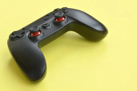 Modern black video game controller on yellow background. Video game speedrun  Stock Photos