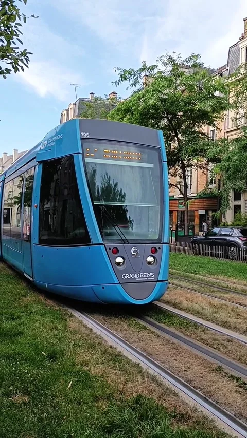 Modern blue tram passing on grass tracks with the historic Reims Cathedral Stock Footage 337967802
