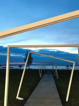 Modern boardwalk with geometric frames over a serene beach sunset Foto stock
