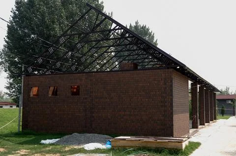 Modern brick building under construction with exposed roof framework Stock Photos