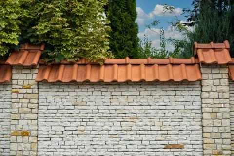 Modern brick pattern of light stone fence wall with tiles in front of a resid Stock Photos